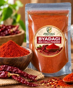 Hilvera Pure Byadgi Red Chilli Powder pouch displayed in kitchen setting with whole dried chillies and spice bowl